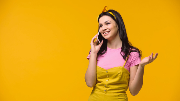 Smiling woman talking on mobile phone isolated on yellow - Φωτογραφία, εικόνα