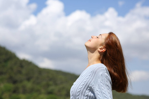 Profile of a woman breathing fresh air in the mountain with a cloudy sky - Foto, imagen