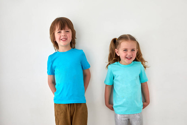 Nette Geschwister in blauen T-Shirts gegen graue Wand - Foto, Bild