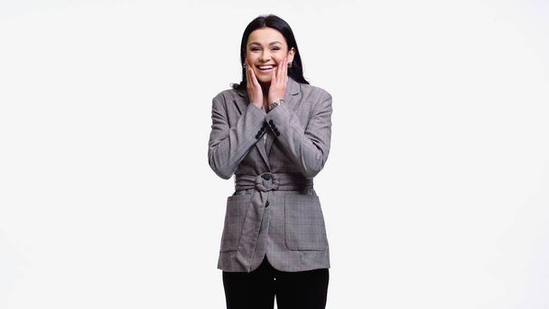Positive businesswoman with hands near cheeks looking at camera isolated on white - Photo, Image