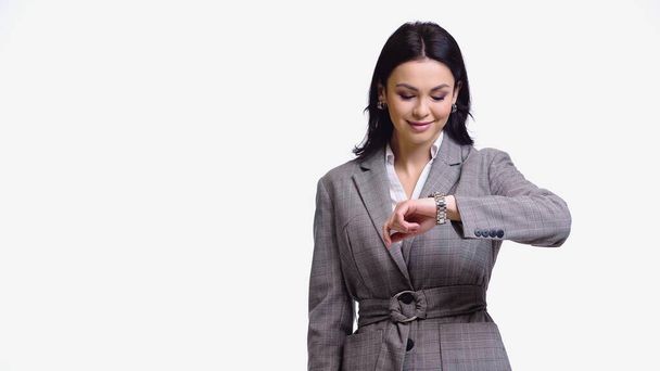 Uśmiechnięta bizneswoman patrząc na zegarek odizolowany na białym  - Zdjęcie, obraz