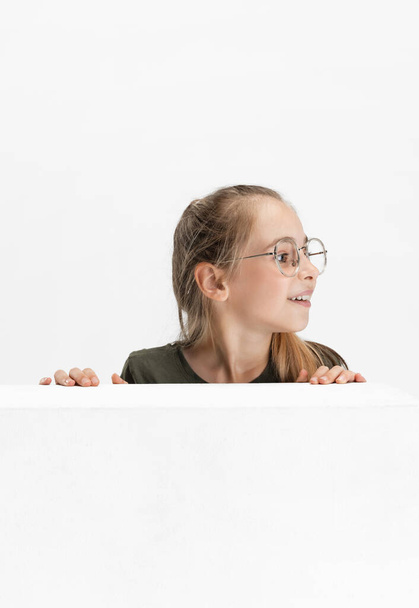 Uma bela menina caucasiana da escola adolescente em roupas casuais e óculos isolados sobre fundo de estúdio branco. - Foto, Imagem