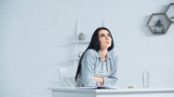 worried businesswoman looking up and breathing while sitting at desk in office - Foto, afbeelding