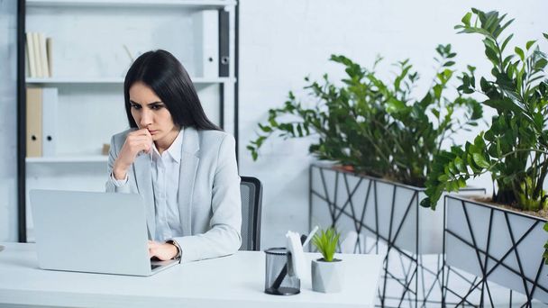 zaniepokojony bizneswoman za pomocą laptopa w nowoczesnym biurze  - Zdjęcie, obraz