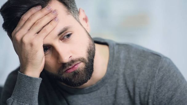 dissatisfied and bearded man touching forehead and looking away - Photo, Image