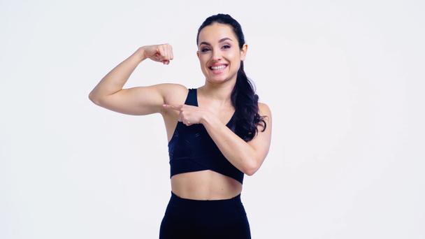smiling sportswoman pointing at muscle isolated on white - Photo, Image