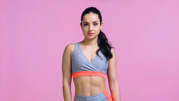 pretty sportswoman in crop top looking at camera isolated on pink - 写真・画像