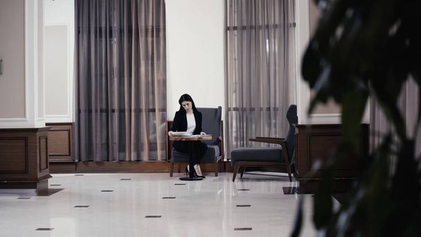 Businesswoman looking at documents in lobby of restaurant  - Fotografie, Obrázek
