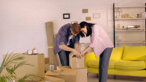 cheerful couple unpacking box in new home - Photo, Image