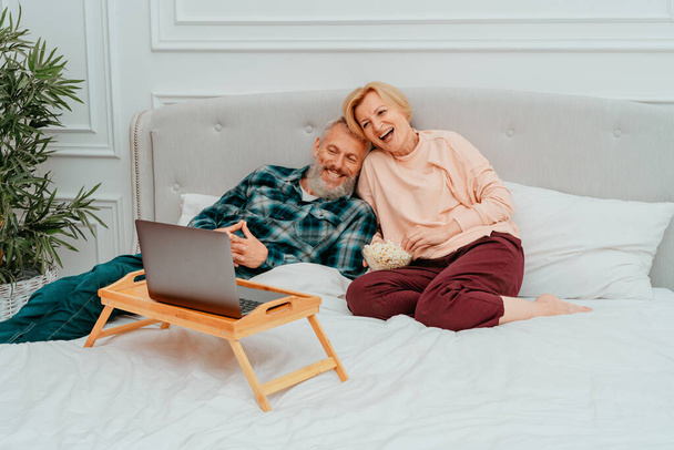 Mann und Frau sehen Film auf dem Bett und essen Popcorn - Foto, Bild