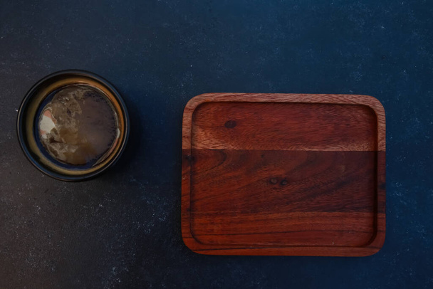 Black coffee mug and blank wooden pad with copy space. Dark cup of espresso, Americano on concrete table background. For coffee shop templates, cafe menu, breakfast concept. Top view - Foto, afbeelding