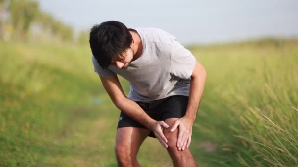 Sportoló ázsiai férfi térd fájdalom edzés után, sérülés az edzés koncepció  - Felvétel, videó