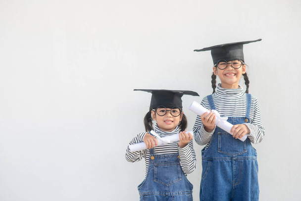 Geschwister Kinder Mädchen Abschluss mit Mütze und Diplom über weiß. - Foto, Bild