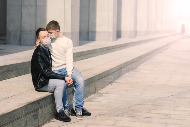 Mladý gayové pár nosit lékařskou masku, objímání a líbání ve městě. - Fotografie, Obrázek