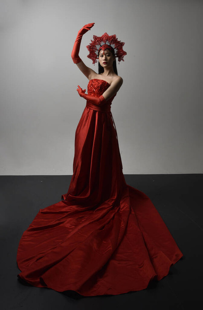 Full length portret van mooie jonge Aziatische vrouw met rood korset, lange operahandschoenen en sierlijke kroon hoofdtooi. Gestural hand poses geïsoleerd op licht studio achtergrond. - Foto, afbeelding