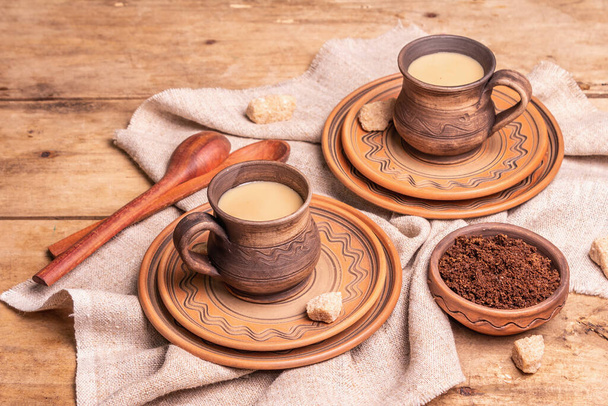 Aromatyczna kawa w przytulnym, domowym stylu. Ceramiczne kubki, gorący napój, drewniany stół. Poranek, dobry nastrój, przestrzeń do kopiowania - Zdjęcie, obraz