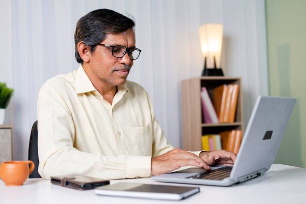 Επιχειρηματίας χαμογελώντας ενώ εργάζεται ή συνομιλεί στο laptop στο γραφείο - έννοια της χρήσης της τεχνολογίας, της επικοινωνίας και του διαδικτύου - Φωτογραφία, εικόνα