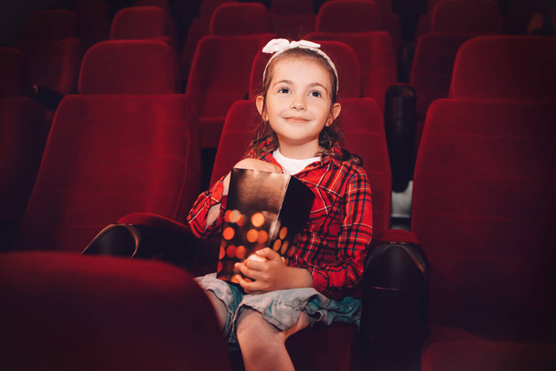 Маленька дівчинка дивиться мультфільм 3D фільм в кіно і їсть попкорн
  - Фото, зображення