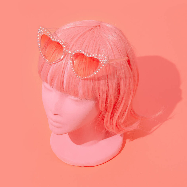 Muchacha retro de moda maniquí en gafas de sol con estilo y pelos de peluca rosa. Tienda de fiestas, vacaciones, concepto de vacaciones. Estilo de los 80 - Foto, imagen