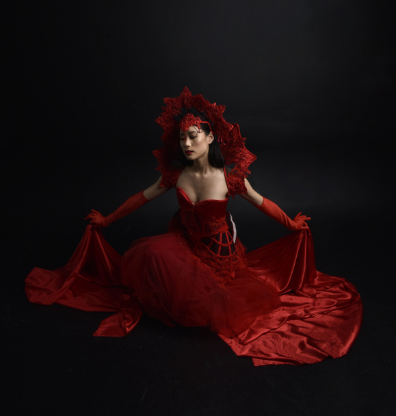 Teljes hosszúságú portré gyönyörű fiatal ázsiai nőről piros fűzővel, hosszú operakesztyűvel és díszes fejdísszel. Kecses pózolás elszigetelt fény stúdió háttér. - Fotó, kép