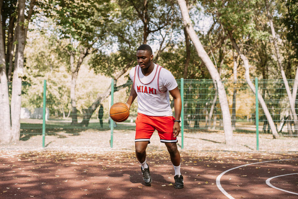 African American basketball player on an outdoor sports ground playing with a ball. doing sports on the street - Zdjęcie, obraz