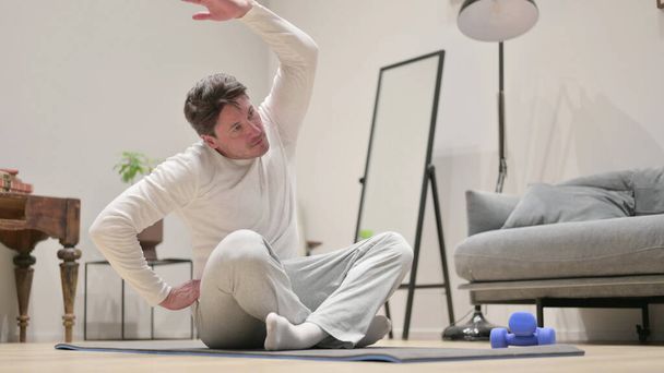 Middle Aged Man doing Stretches at Home - Foto, afbeelding