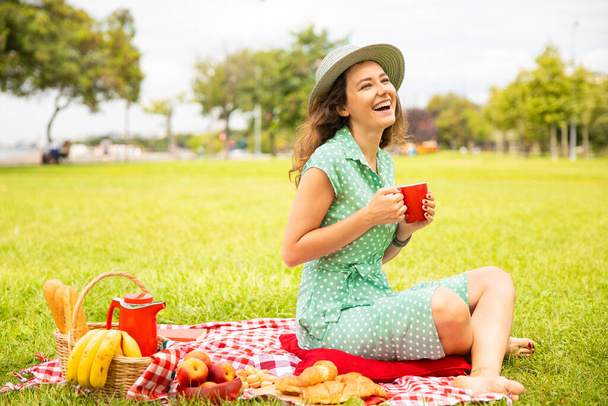 Beautiful young woman having picnic on sunny spring day in par - Foto, afbeelding