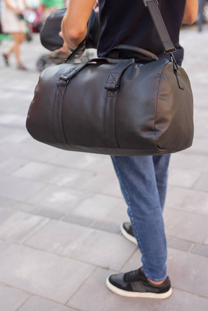 Hombre caminando en la ciudad con bolsa de cuero negro - Foto, imagen