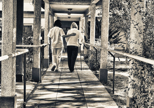 Médico asiático que ayuda a las mujeres mayores jubiladas con bastón de paseante en el patio del hospital. Concepto de rehabilitación. - Foto, imagen
