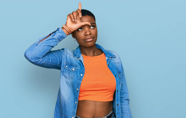 Mladá africká americká žena na sobě ležérní oblečení dělat si legraci z lidí s prsty na čele dělat poražený gesto posměch a urážlivé.  - Fotografie, Obrázek