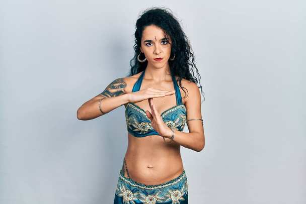 Молода жінка в бінді і традиційному танцювальному одязі живота робить жест часу руками, розчарованим і серйозним обличчям
  - Фото, зображення