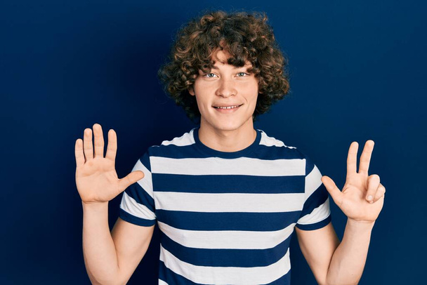 Handsome young man wearing casual striped t shirt showing and pointing up with fingers number eight while smiling confident and happy.  - Photo, Image
