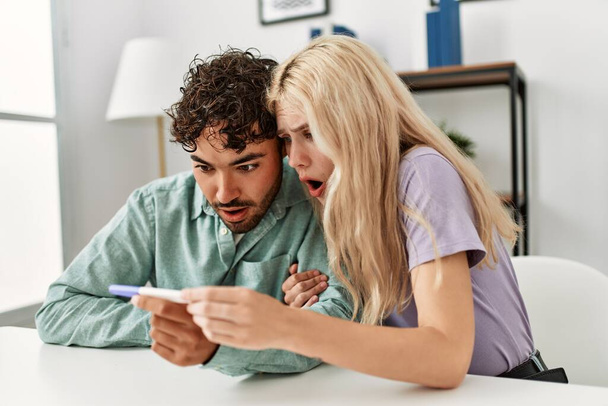 Jeune couple surpris regardant résultat de test enceinte à la maison. - Photo, image