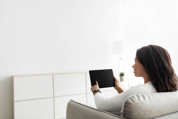 Smart Home Konzept. Millennial Frau mit digitalem Tablet mit leerem Bildschirm, Anpassung der Automatisierungsprozesse im Haus - Foto, Bild