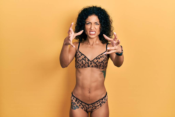 Joven chica latina con bikini gritando frustrado por la rabia, las manos tratando de estrangular, gritando loco  - Foto, Imagen