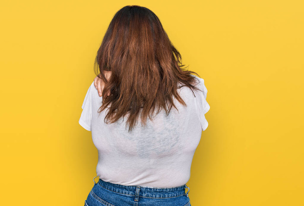 Junge Plus-Size-Frau in lässigem weißem T-Shirt, die sich glücklich und positiv von hinten umarmt. Selbstliebe und Selbstfürsorge  - Foto, Bild