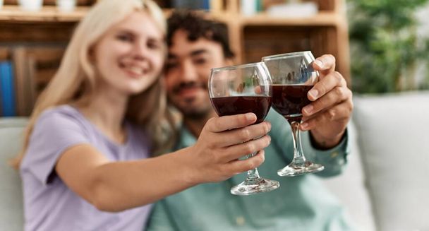 Fiatal pár mosolyog boldog pirítóst vörösbor pohár otthon. - Fotó, kép