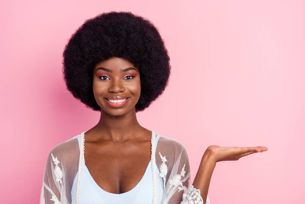 Photo of positive charming young dark skin woman hold hand empty space sale isolated on pink color background - Fotografie, Obrázek