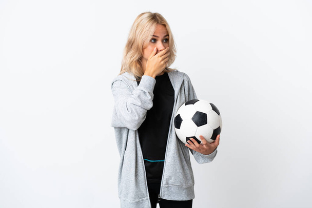 Nuori venäläinen nainen pelaa jalkapalloa eristetty valkoisella taustalla kattaa suun ja etsivät sivuun - Valokuva, kuva