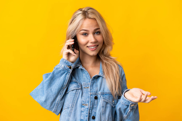 Young Russian woman isolated on yellow background keeping a conversation with the mobile phone with someone - Foto, immagini