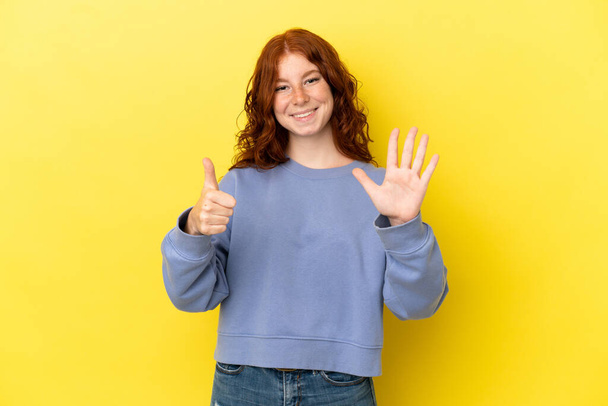 Teenager rötliche Frau isoliert auf gelbem Hintergrund zählen sechs mit den Fingern - Foto, Bild