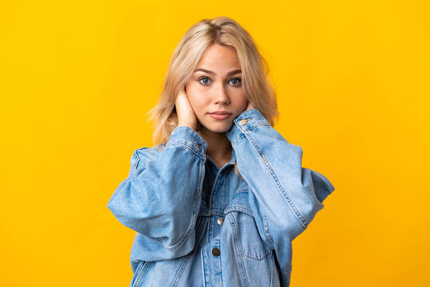 Young Russian woman isolated on yellow background frustrated and covering ears - Foto, Bild