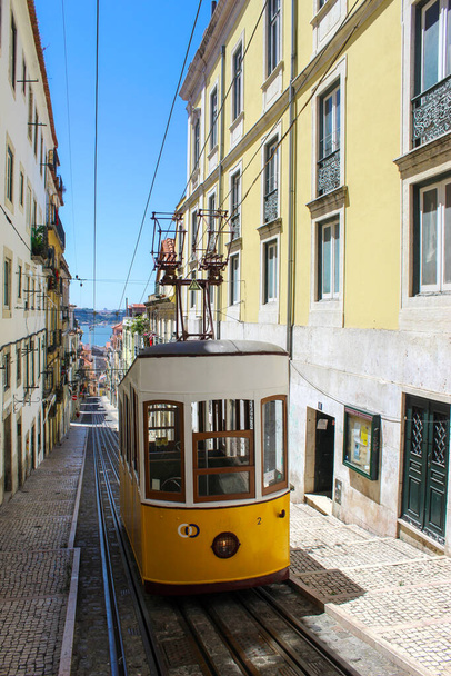 Vintage τραμ στο κέντρο της πόλης της Λισαβόνας σε μια όμορφη καλοκαιρινή μέρα, Πορτογαλία. Παραδοσιακό κίτρινο τραμ σε ένα δρόμο στη Λισαβόνα, Πορτογαλία. - Φωτογραφία, εικόνα
