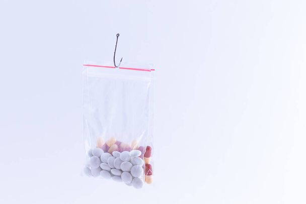 Colored Pills or Tablets Hanging in Small Ziplock Bag on a Fishing Hook - Photo, Image
