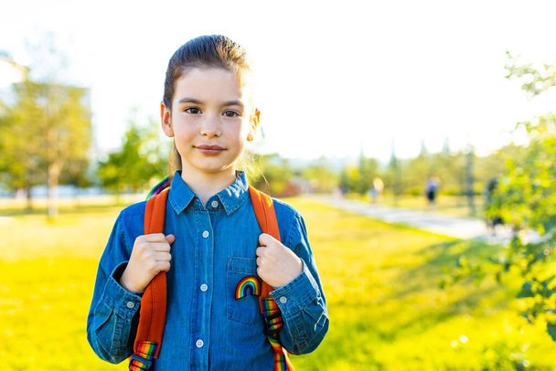 Niña estudiante india sonriente con mochila escolar y camiseta azul en el parque - Foto, imagen