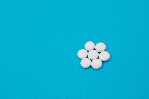 Farmaceutický průmysl a léčivé přípravky - Bílé pilulky na modrém stole - Fotografie, Obrázek