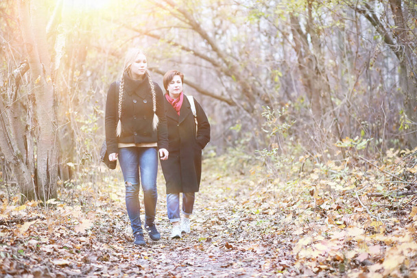 Mladá dívka s matkou na procházce v podzimní zahradě - Fotografie, Obrázek
