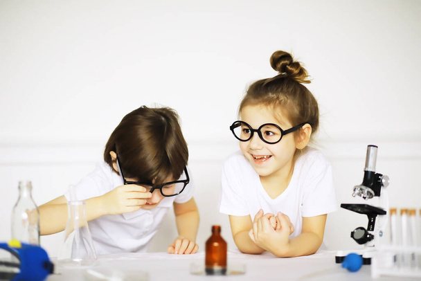 Dos niños lindos en la lección de química haciendo experimentos aislados en el fondo blanco - Foto, imagen
