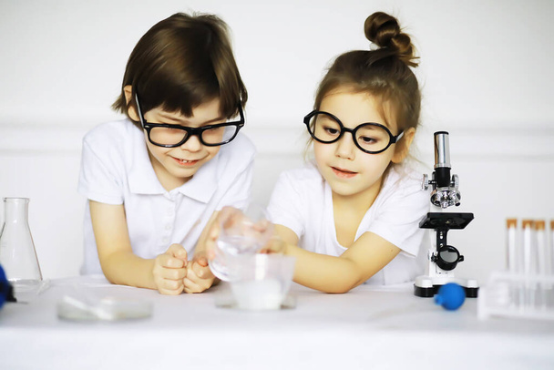 Два милых ребенка на уроке химии делают эксперименты изолированными на белой спине - Фото, изображение