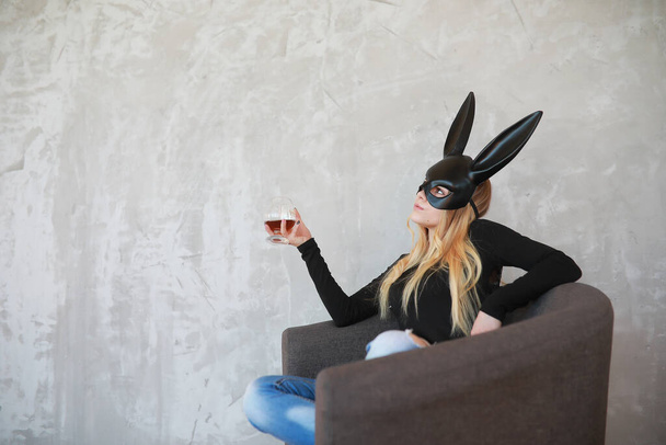 Ein Mädchen in schwarzer Maske mit langen Ohren im Studio - Foto, Bild